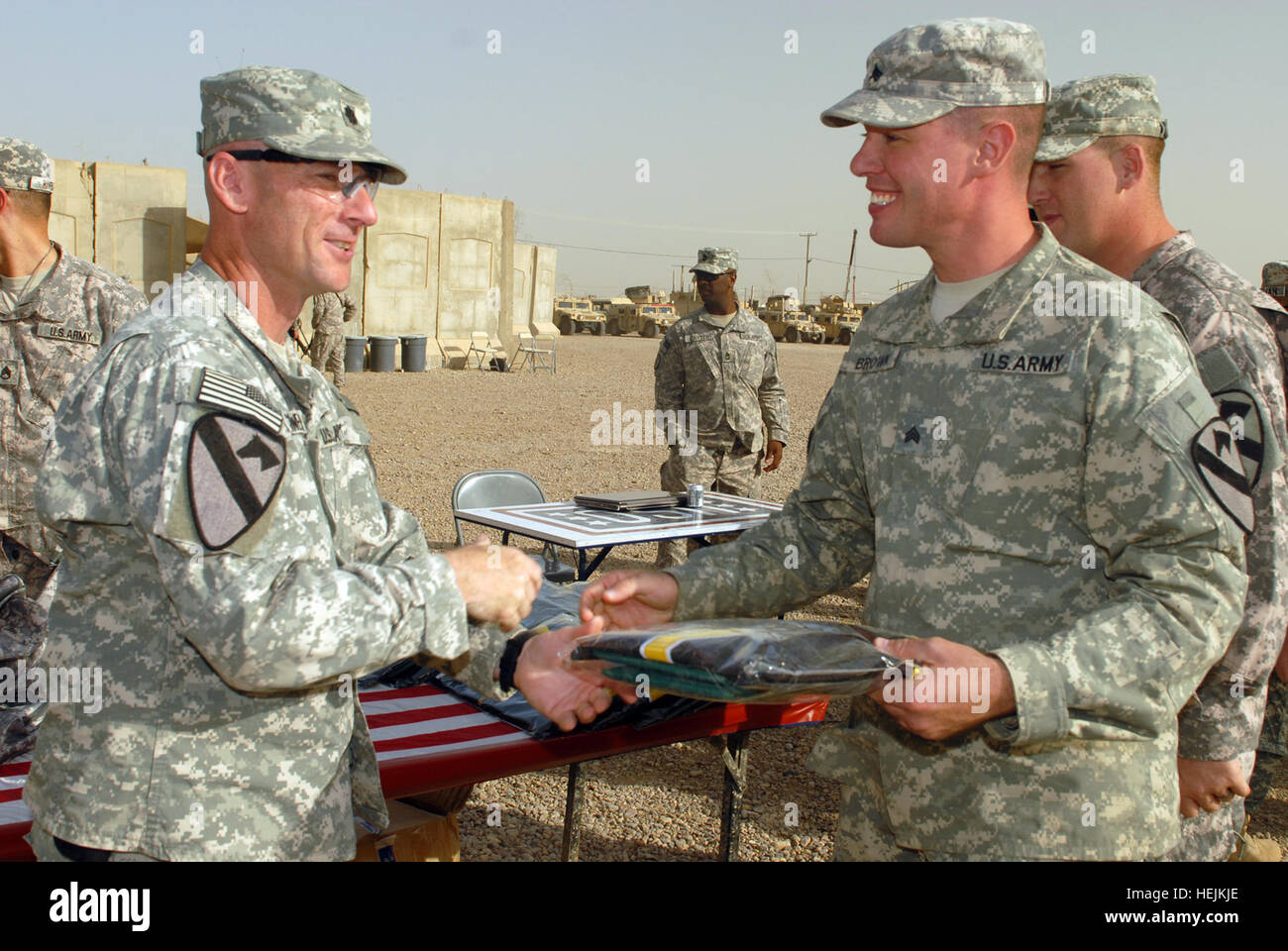 Lt. Col. Eric Schwegler (left), of Ozark, Ala., presents an 'Ironhorse' Brigade jersey to Sgt. James Brown of Binghampton, N.Y. Schwegler is commander of the 1st Battalion, 82nd Field Artillery Regiment, 1st Brigade Combat Team, 1st Cavalry Division. Brown, a track vehicle mechanic, said he re-enlisted so he could make retirement in the Army. 'I didn't do it for the money because I didn't get any,' joked Brown, who is assigned to Company G, 1st Bn., 82nd FA Regt. 'I know I am taking care of my family and reaching my goal of retirement.' Brown was one of 83 'Dragon' Battalion Soldiers who have  Stock Photo