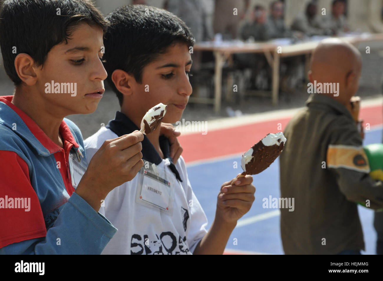 Two Iraqi children eat ice cream at Joint Base Balad, Iraq, Oct. 10, 2009 during a kids' day hosted by the Air Force here. Children were brought on base to learn fire safety, play games and interact with their military mentors. Service members donate time, goods to Iraqis 227214 Stock Photo