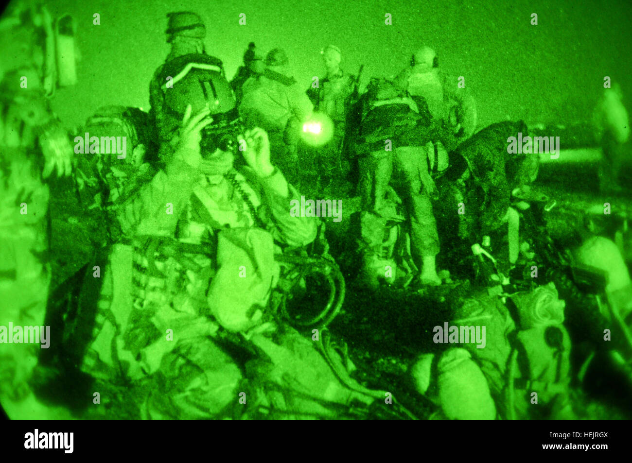 An Afghan soldier with 3rd Commando Kandak makes adjustments to his mounted night vision device while fellow Commandos and U.S. soldiers with Special Operations Task Force - South conduct final mission preparation before conducting an operation to remove insurgents from Lam village, Khakrez District, Nov. 14, 2010, Kandahar province, Afghanistan. Taliban Insurgents Surrender to Afghan, Coalition Forces in Kandahar 341279 Stock Photo