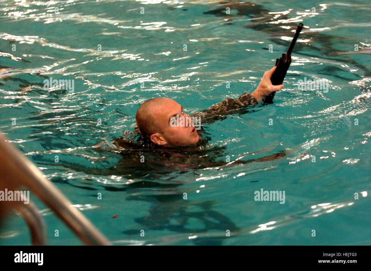 A Soldier with the 2nd Brigade Combat Team, 101st Airborne Division, (Air Assault) swims toward the pool's ladder with his weapon above the water's surface during the combat water survival and confidence assessment portion of the Strike Ranger Assessment Program while at Gardner Indoor Pool, Dec. 3. The brigade's program is a weeklong process done every month to select which Soldiers will represent the Strike Brigade at the extremely difficult U.S. Army Ranger School. Strike prepares its Soldiers for Ranger School 239560 Stock Photo