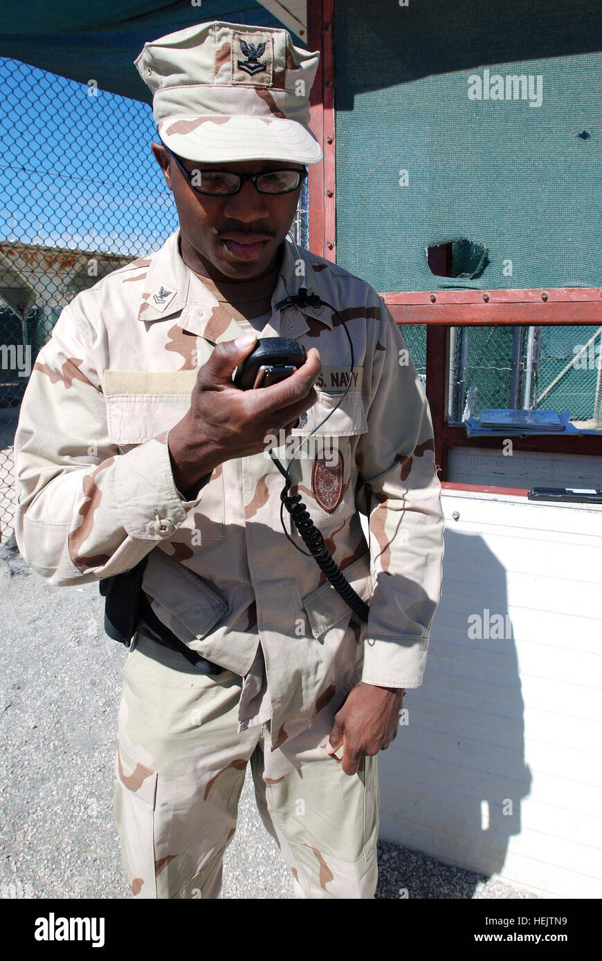 GUANTANAMO BAY, Cuba – Navy Petty Officer 2nd Class Corenzo King, an operations specialist with Joint Task Force Guantanamo's Navy Expeditionary Guard Battalion, receives a call on his radio while on watch at Camp 4, part of JTF Guantanamo, Dec. 7, 2009.  The NEGB provides a portion of the guard force inside Joint Task Force Guantanamo’s detention facilities. JTF Guantanamo conducts safe, humane, legal and transparent care and custody of detainees, including those convicted by military commission and those ordered released by a court. The JTF conducts intelligence collection, analysis and diss Stock Photo