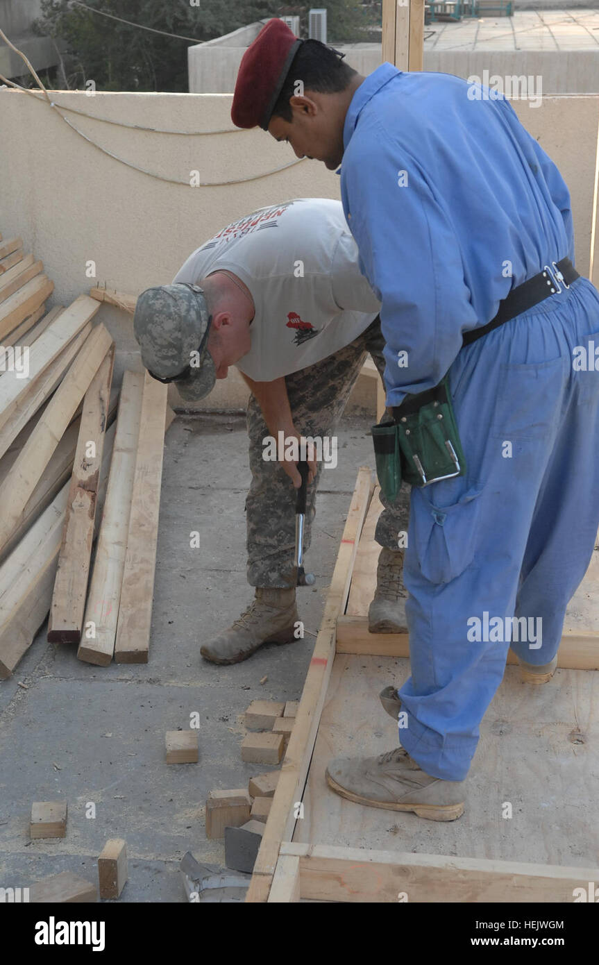 U.S. Army Staff Sgt. Joshua Weinland, assigned to the 5-2nd Federal Police Training Team, attached to the 30th Heavy Brigade Combat Team, 1st Cavalry Division, works with an Iraqi contractor during Joint Schoolhouse Construction project, Saydiyah, Iraq, Dec. 16. Members of the 5-2nd Federal Police Training Team, attached to the 30th HBCT, 1st Cavalry Division, are helping to improve many of the schoolhouses in their area of operations to build better learning environments for Iraqi children. Operation Iraqi Freedom 235092 Stock Photo