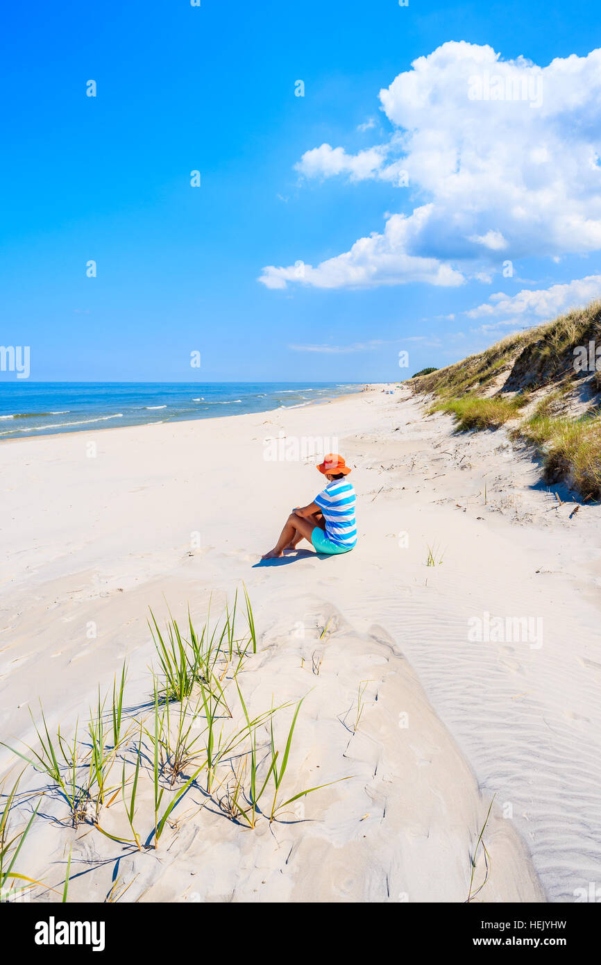 Young woman sitting on sand on Lubiatowo beach, Baltic Sea, Poland Stock Photo
