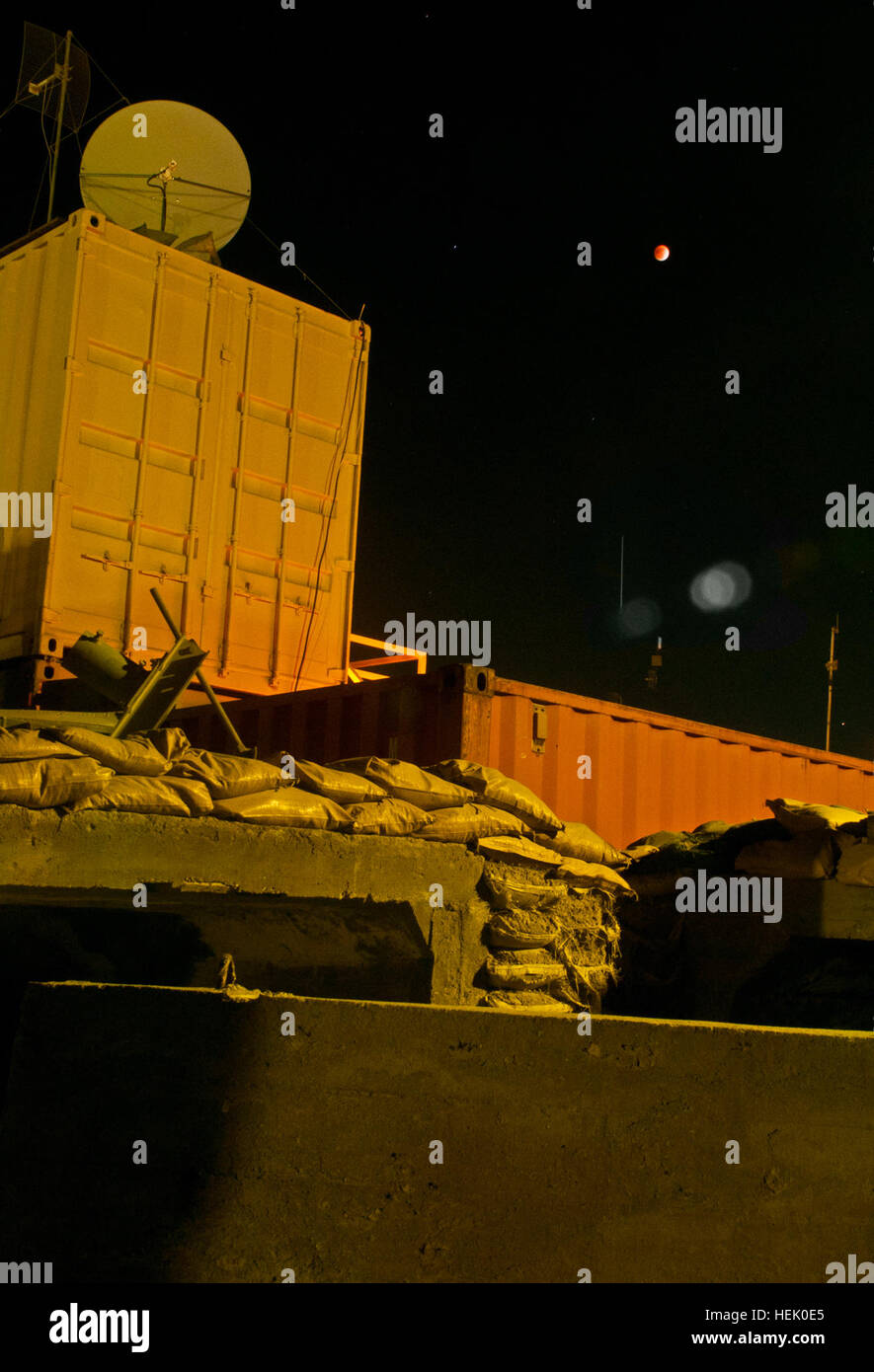 The shadow of the sun passes over the moon above shipping containers ...