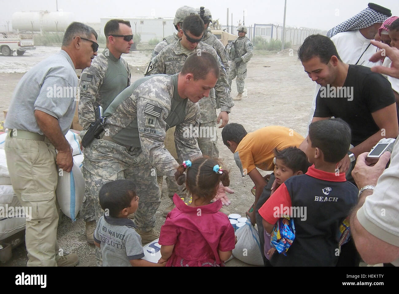 Lt. Col. Robert Wright, commander of Task Force Steel Dragon, 2nd Battalion, 82nd Field Artillery Regiment, 3rd Advise and Assist Brigade, 1st Cavalry Division, hands out bags and packets of humanitarian aid to Iraqi families with Capt. Josh Holden and 2nd Lt. Christopher Molaro July 3, 2011. (Photo by 2nd Lt. Christopher Molaro) Steel Dragons partner with local sheik to support Iraqi families 425136 Stock Photo