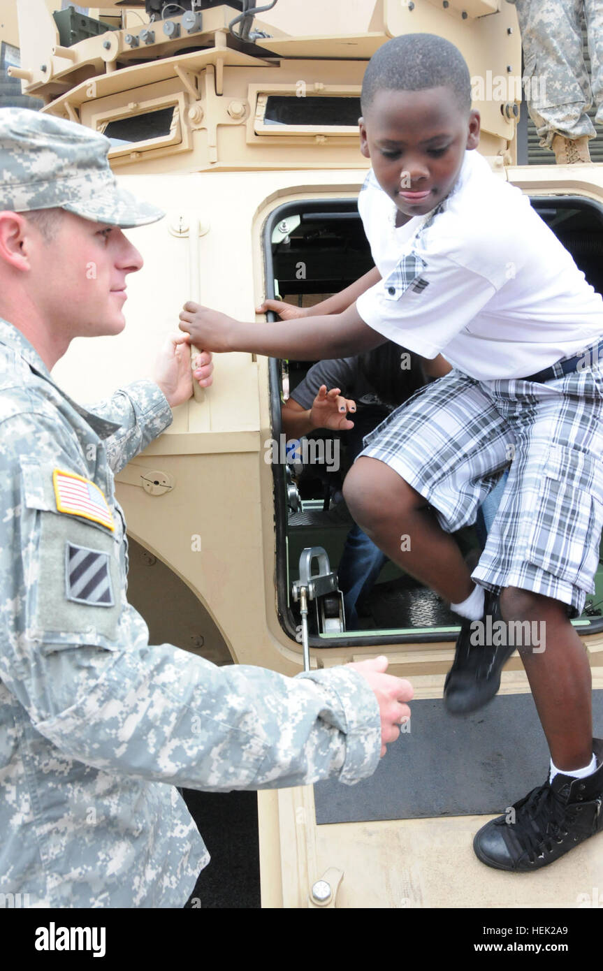 Sgt. Mikale Urizar, a forward observer with Headquarters and Headquarters Battery, 1st Battalion, 76th Field Artillery Regiment, 4th Infantry Brigade Combat Team, 3rd Infantry Division, helps a Button Gwinnett Elementary School student climb out of the M1200 Armored Knight, May 18. 'Patriot' soldiers showcased the Knight and the High Mobility Multipurpose Wheeled Vehicle during the school's career day in Hinesville, Ga. Field artillery soldiers showcase military vehicles for elementary students 120518-A-CE832-019 Stock Photo