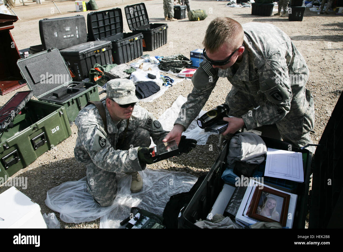 Sgt. Ronnie Head (left), a member of the Alabama National Guard, 217th Military Police Company, 336th MP Battalion, 49th MP Brigade, physically inspects the personal property of Spc. Jarrod Smith, a wheeled vehicle mechanic with the 1st Medical Brigade Headquarter's Company, prior to sealing it into a 25-foot shipping container. The Fort Hood, Texas-based , medical company will redeploy within the upcoming weeks, and resume its  CONUS (continental United States) mission. 49th Military Police Brigade Conduct Customs Operations in Iraq 272429 Stock Photo