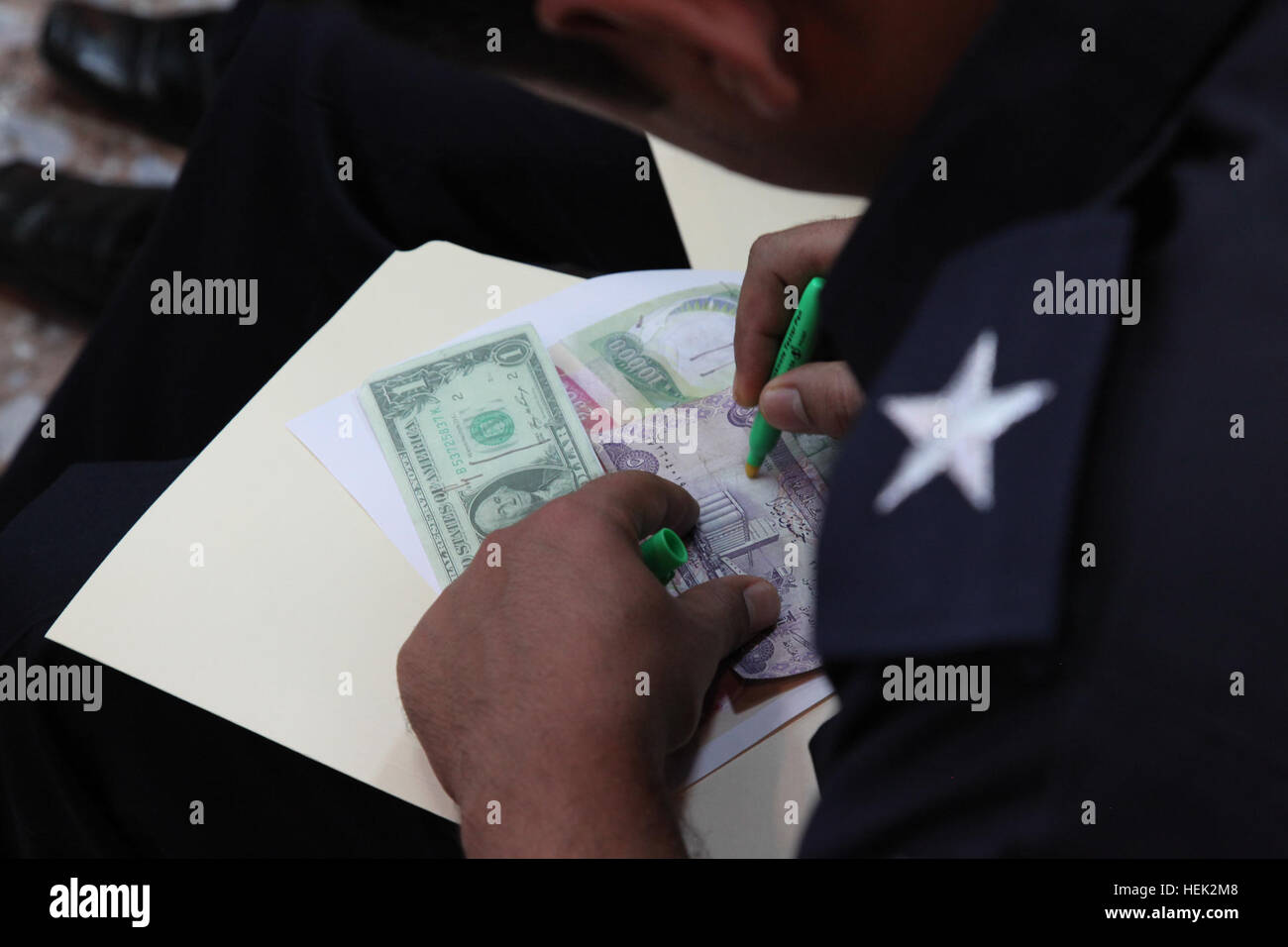 An Iraqi police lieutenant tests the validity of the dollar, the euro
