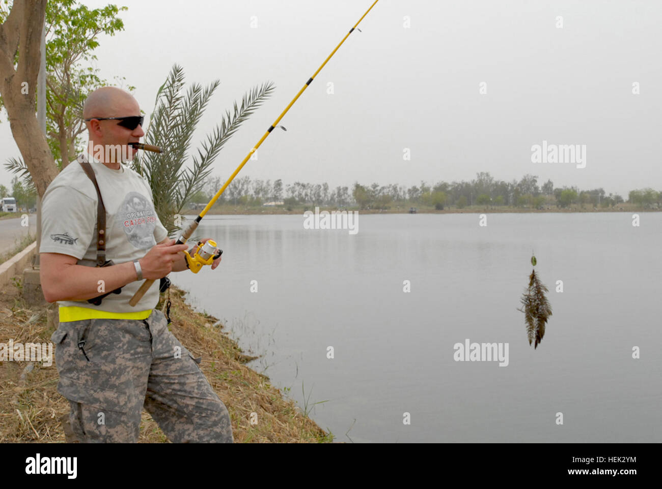 Louisiana National Guard Soldiers with the 256 Infantry Brigade Combat Team enjoyed a day of fishing with Operation Catch Fish, III, hosted by Joe Mercurio, Sheli Sanders, Mary Delgado and Gary Hain with special guests New Orleans Saints' Saintsations. OCF came to the Victory Base Complex in Baghdad, Iraq, April 28, to entertain and boost the morale of Troops in theatre in support of Operation Iraqi Freedom. Tiger Brigade Soldier Sgt. 1st Class Jason M. Mendel, non-commissioned officer in charge of an entry control point, from Abbeville, La., tries to relax with his cigar while reeling in his  Stock Photo