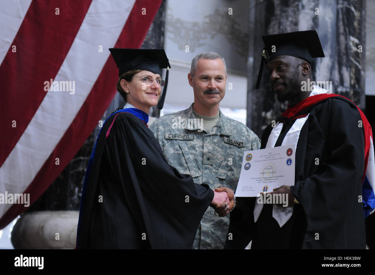 A graduate (right) receives an Embry-Riddle Aeronautical University master of science in safety science education center certificate from Brig. Gen. Donald J. Currier (center), commander of the 49th Military Police Brigade, and Carolyn L. Baker (left), chief of continuing education programs, Office of the Secretary of Defense. Service members graduate while deployed 283580 Stock Photo