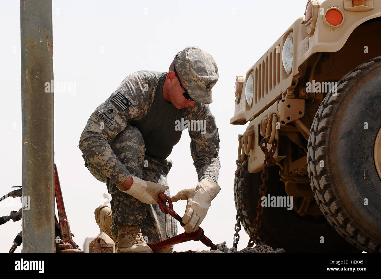 Staff Sgt. Jeremy Burkett, motor vehicle operator, 2101st Transportation Company, 541st Combat Sustainment Support Battalion, 3rd Sustainment Brigade, 13th Sustainment Command (Expeditionary) and a native of Brundidge, Ala., adjusts chains used to securely fasten a load to his truck, June 17, in the motor pool on Contingency Operating Base Speicher, Iraq. Celebrated Alabama unit rolls with tide of cargo 293752 Stock Photo