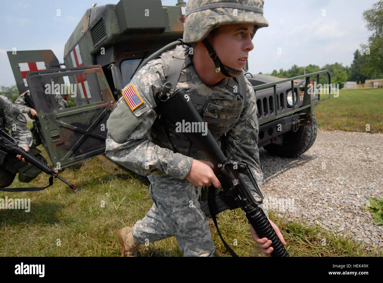 Pfc. Noah Grant, a medic in Ambulance Platoon, 738th Area Medical Support Company headquartered in Lafayette, Ind., sprints from his ambulance after a simulated ambush during a training exercise at the Camp Atterbury Joint Maneuver Training Center in central Indiana, June 23. Grant is part of the 81st Troop Command and was conducting annual training at Camp Atterbury. Combat Medics React to Simulated Ambush, Camp Atterbury 293849 Stock Photo