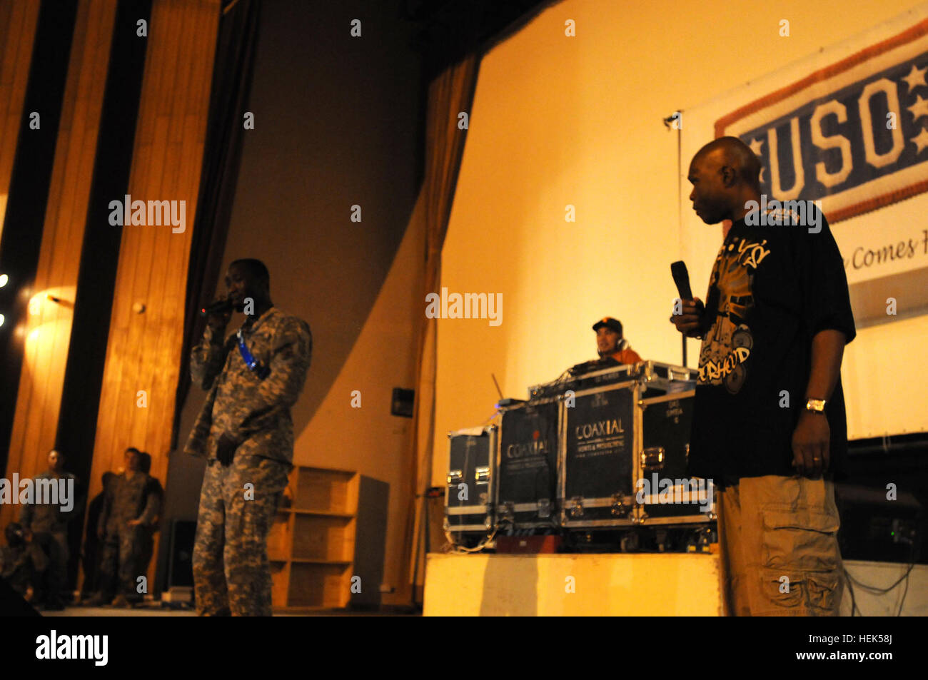 Cpl. Lawrence Lee, a supply sergeant for Headquarters and Headquarters Company, 3rd Suppport Brigade, 103rd Sustainment Command (Expiditionary), and a Pensacola, Fla., native, sings on stage while entertainer Big Boy watches on Aug. 6, at Joint Base Balad, Iraq. This was part of the festivities leading up to a performance by rapper Paul Wall. (U.S. Army photo by Pfc. Adrian Muehe) Rapper Paul Wall Mixes Up the Sand at JBB 308648 Stock Photo