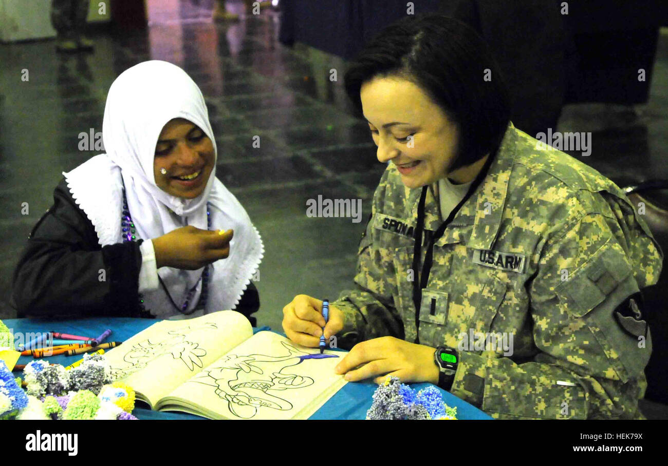 1st Lt. Susan Sponable, Budget Analyst with the 36th Engineer Brigade, colors a picture with little Sanaa, one of the Iraqi children invited to Iraqi Kids Day at Joint Base Balad, Iraq, Nov. 5. The children also got a chance to play sports outside with voluntee service members. Iraqi Kids Day 338189 Stock Photo