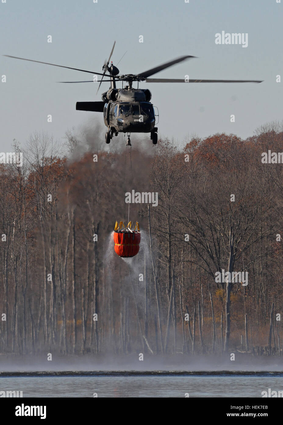 A Blackhawk helicopter fills a collapsible water bucket with