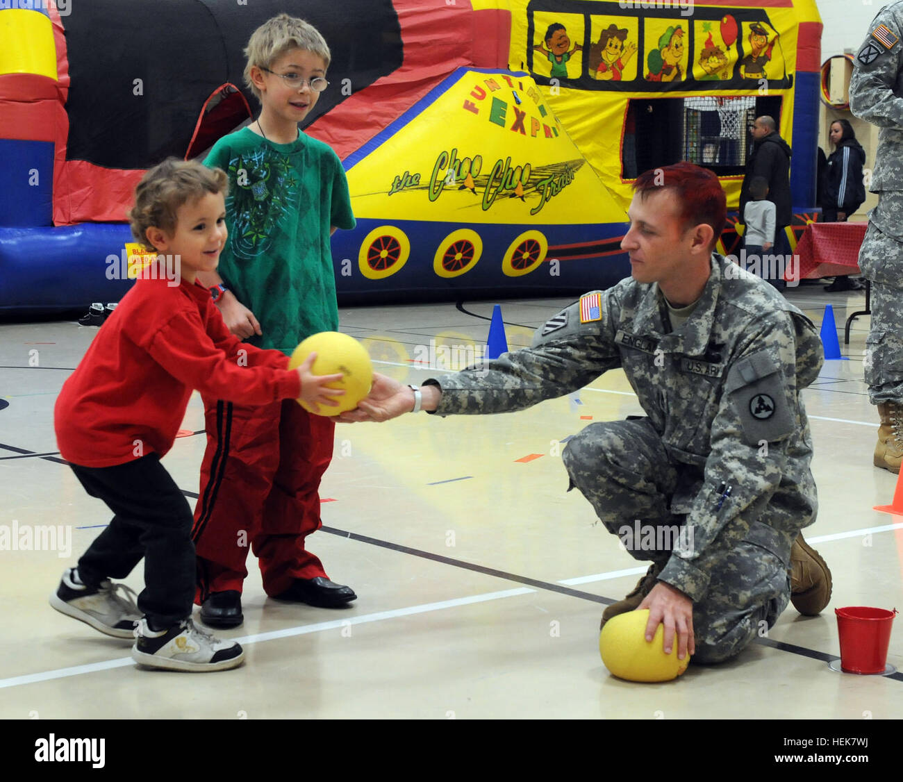Sgt. 1st Class Andrew England, with the 3rd Sustainment Command (Expeditionary), hands a bowling ball to a Pierce Elementary School student at the school's Winter Festival Dec. 2. England and about 24 other soldiers from the 3rd ESC volunteered their time to assist with the school's festival. Sustainers Give Back at Pierce Elementary Winter Fest 347108 Stock Photo