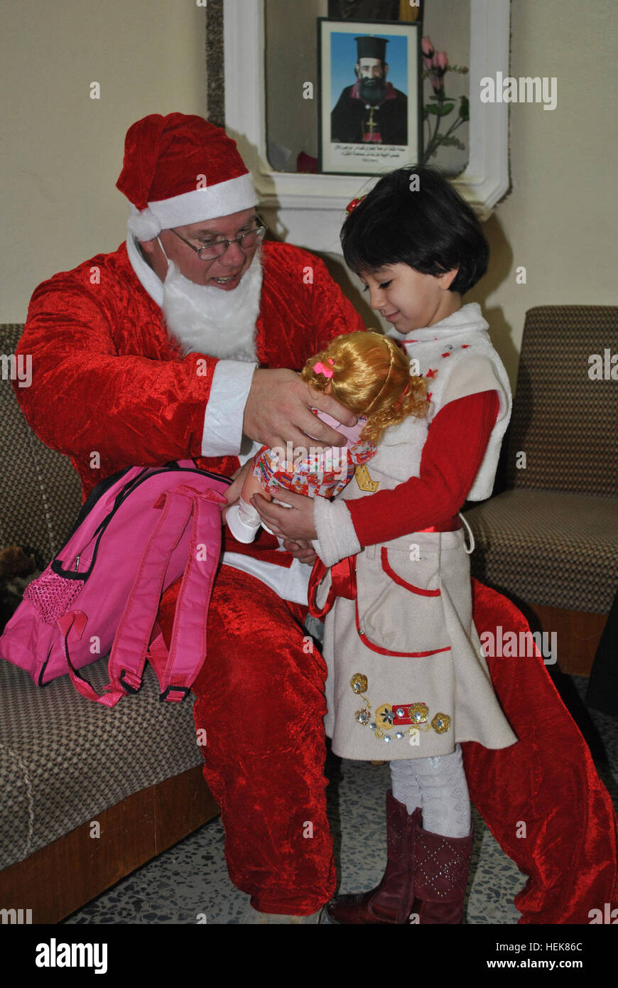 Maj. Michael Patterson, senior chaplain assigned to 4th Advise and Assist Brigade, 1st Cavalry Division, dressed as Iraq's Baba Noel, known more commonly in the United States as Santa Claus, gives a doll to a young Iraqi girl during a religious leader engagement at the Church of Mar Youhanna, or Saint John, in the town of Qara Qosh, Dec. 14, 2010. The gifts were collected through a team of soldiers from the U.S. Army Reserve 412th Civil Affairs Battalion, from Columbus, Ohio, attached to 4th AAB, 1st Cav Div. Patterson, a Vero Beach, Fla.-native, said he wanted to bring the Christmas spirit to Stock Photo