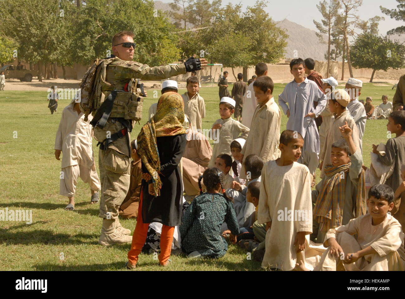 KANDAHAR, Afghanistan – Staff Sgt. Mark Masters, currently assigned to 1st Brigade Combat Team, Task Force ‘Raider’, 4th Infantry Division, directs a group of local children to where they can watch a soccer game between two local teams June 8. The game occurred after a ribbon cutting ceremony which signified the official opening of a new soccer field in sub district one of Kandahar City. The new field was one of many projects headed by TF ‘Raider’ and their Afghan National Security Forces partners in their joint-reconstruction efforts to improve quality of life, safety and security for residen Stock Photo