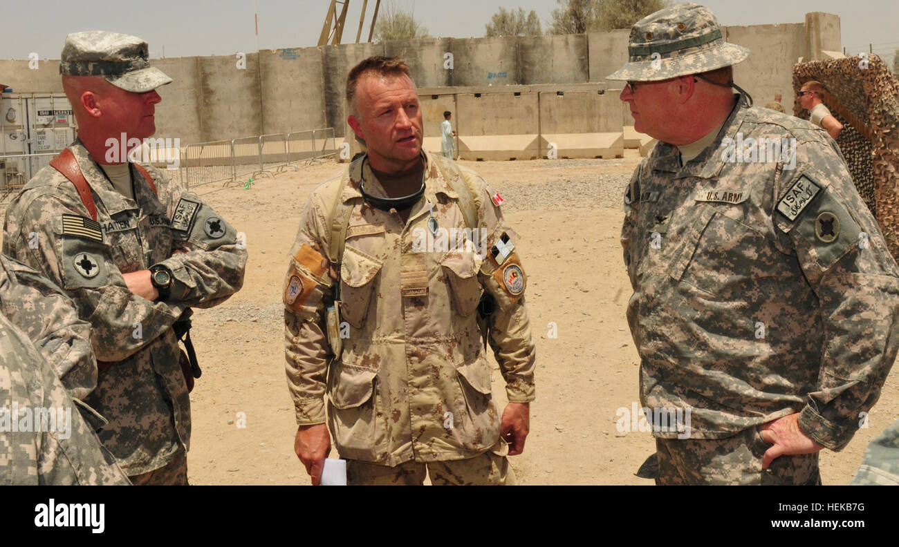 (Left) U.S. Army Sgt. Maj. William Hatten, Joint Sustainment Command –Afghanistan operations sergeant major and (right) Col. Richard Martin, JSC-A operations officer discuss operations with Canadian Lt. Col. Steve Davenport, Kandahar Airfield Bazaar School representative at KAF June 25. Mississippi Army National Guard soldiers donate backpacks and school supplies to Afghan children 424493 Stock Photo