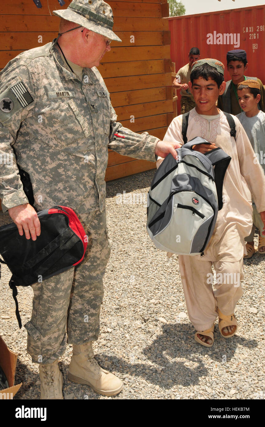 (Left) U.S. Army Col. Richard Martin, Joint Sustainment Command–Afghanistan operations officer, hands a backpack filled with school supplies to a local Afghan boy attending the Kandahar Airfield Bazaar School June 25. Martin is a member of the Mississippi Army National Guard’s 184th Expeditionary Sustainment Command, which has been deployed to Afghanistan in support of Operation Enduring Freedom since early October. The school supplies were provided through a unique collaboration between Mid Gulf Forestry Inc. and students from Parklane Academy in McComb, Miss. Mississippi Army National Guard  Stock Photo