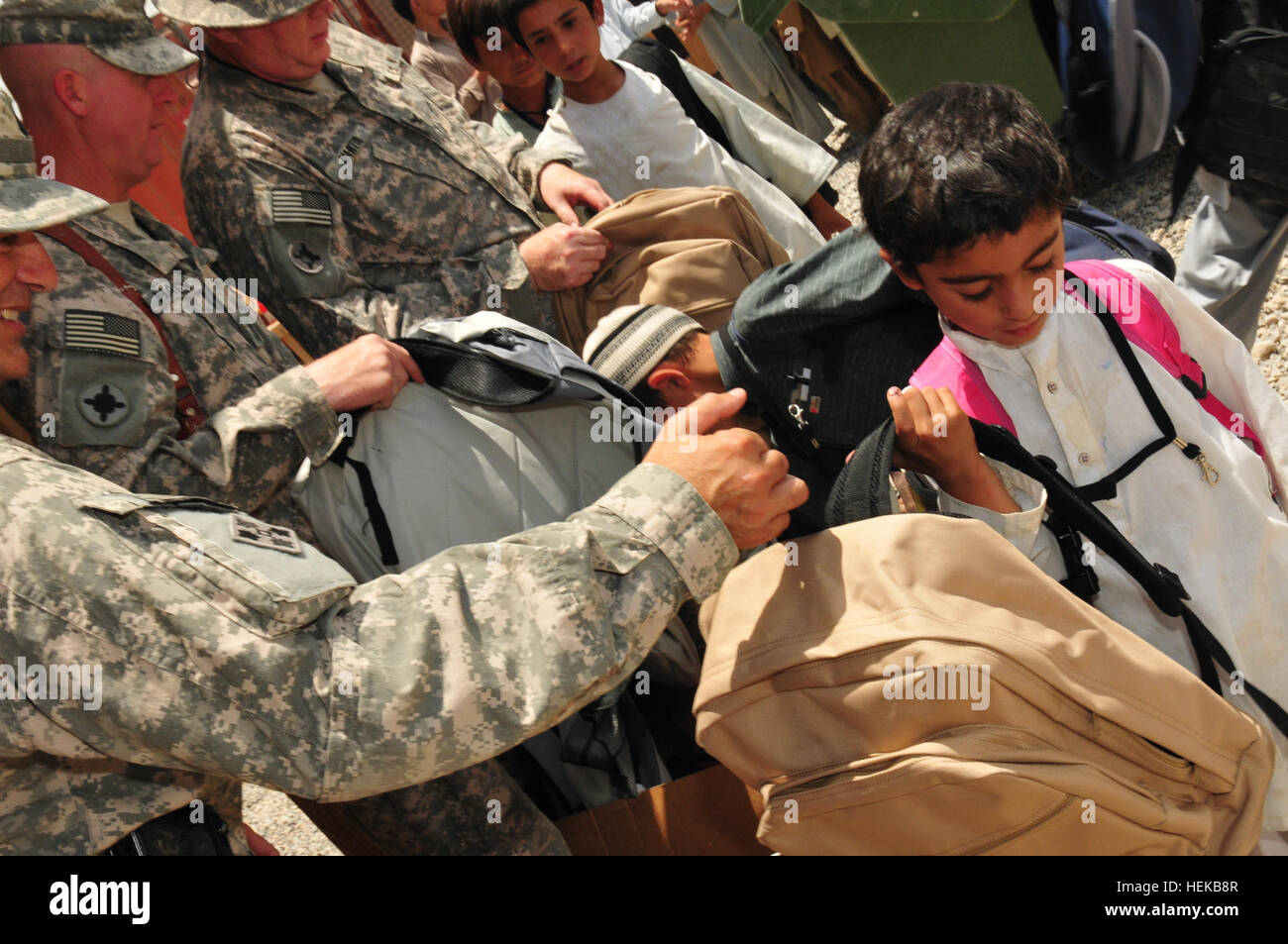 A local Afghan boy receives a backpack filled with school supplies from U.S. Army Lt. Col. Antonio Sanabria, 101st Sustainment Brigade liaison officer assigned to Joint Sustainment Command-Afghanistan, at the Kandahar Airfield Bazaar School June 25. The school supplies were provided through a unique collaboration between Mid Gulf Forestry Inc. and students from Parklane Academy in McComb, Miss. Mississippi Army National Guard soldiers donate backpacks and school supplies to Afghan children 424606 Stock Photo
