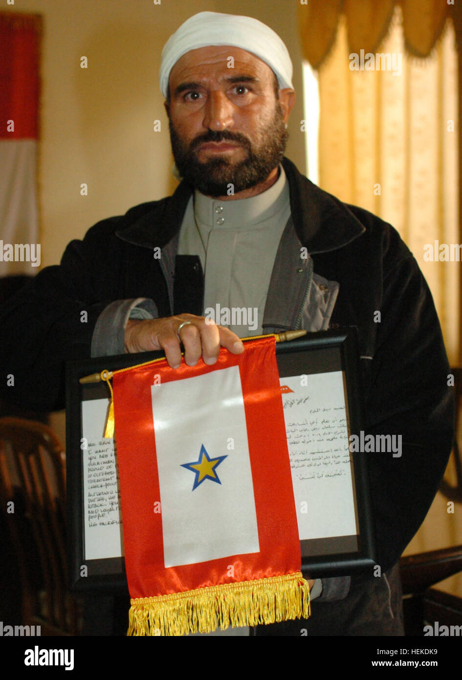 Zaynal Hassan Wahab holds up the plaque and the gold star flag presented to him by U.S. Army Maj. Gen. Benjamin R. Mixon, commander of the 25th Infantry Division, at a small ceremony in Tal Afar Oct.14, 2006. Mixon presented the gold star flag to Wahab in honor of his son, Iraqi police officer Suliman Zaynel Hassan, who was killed Oct. 9. Iraqi Police Officer Honored by U.S. Commander 33551 Stock Photo