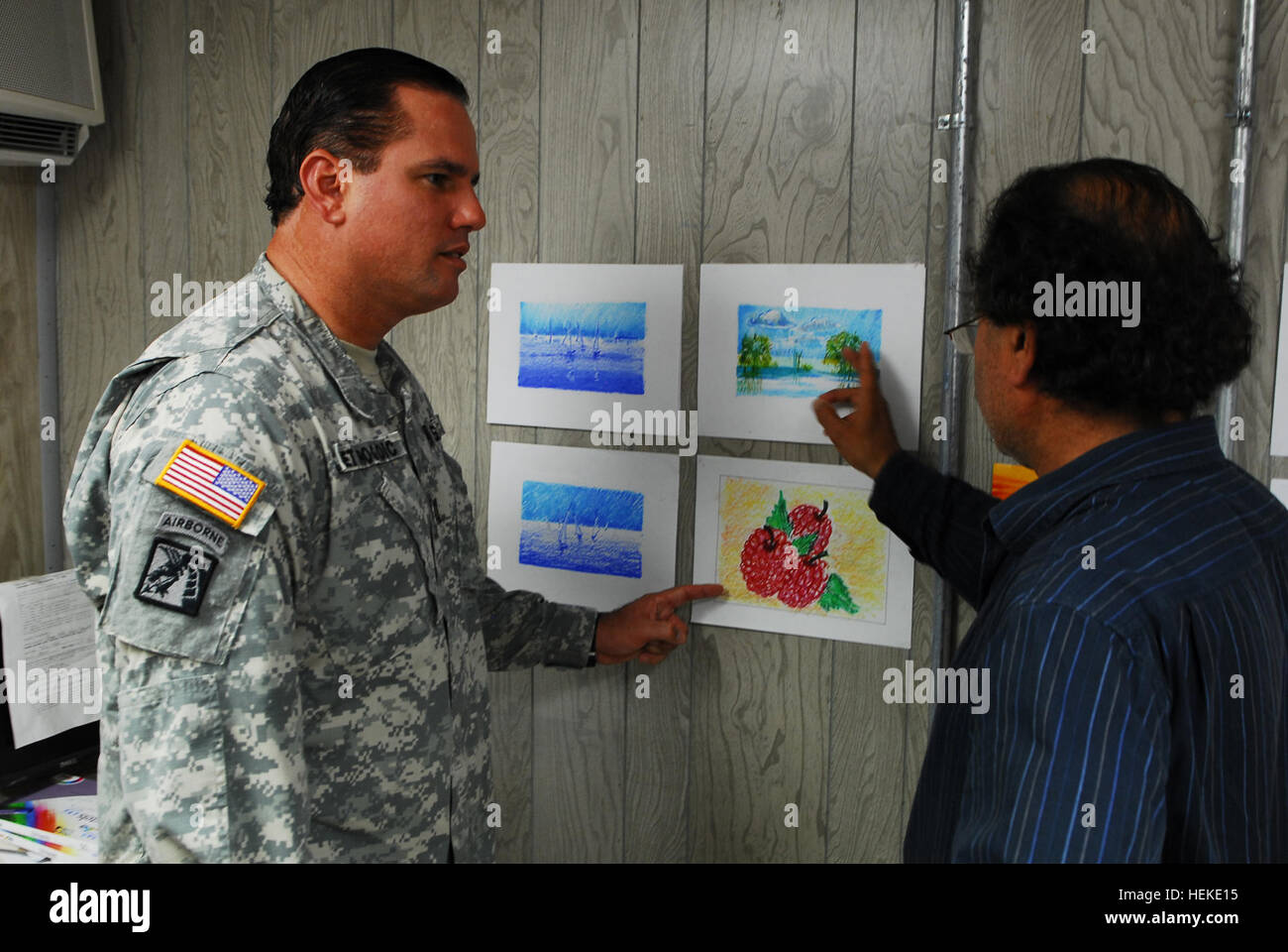 GUANTANAMO BAY, Cuba – Army Capt. Jose Izquierdo, Joint Task Force Guantanamo’s officer-in-charge of detainee programs, receives an update from Adam, the art instructor, on the art work produced by the detainees, Aug. 4, 2009. The art program provides intellectual stimulation for the detainees, and allows them to express their creativity. JTF Guantanamo conducts safe, humane, legal and transparent care and custody of detainees, including those convicted by military commission and those ordered released by a court. The JTF conducts intelligence collection, analysis and dissemination for the pro Stock Photo