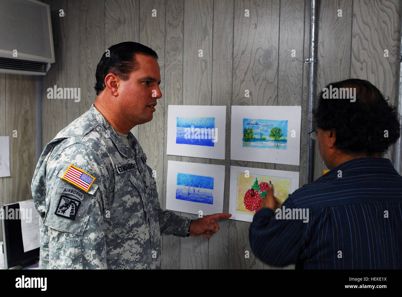 GUANTANAMO BAY, Cuba – Army Capt. Jose Izquierdo, Joint Task Force Guantanamo’s officer-in-charge of detainee programs, receives an update from Adam, the art instructor, on the art work produced by the detainees, Aug. 4, 2009. The art program provides intellectual stimulation for the detainees, and allows them to express their creativity. JTF Guantanamo conducts safe, humane, legal and transparent care and custody of detainees, including those convicted by military commission and those ordered released by a court. The JTF conducts intelligence collection, analysis and dissemination for the pro Stock Photo
