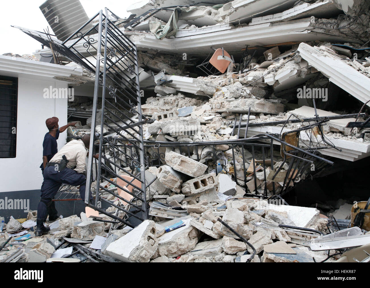 December 23, 2016 - Port-Au-Prince, Florida, U.S. - 011910 (Lannis Waters/The Palm Beach Post) PORT-AU-PRINCE, HAITI - A Haitian police officer and another man look in the ruins of the University of Port-au-Prince. A man said he called the cellphone of his girlfriend, Andree Rose Gilles (cq), Sunday and got a response. Gilles was a student inside at the time of the earthquake. Her sister, Misnite Gilles (cq), 27, was rescued after being buried in the school for 4 days. Schools of all types all over Port-au-Prince were destroyed in the earthquake, leading to the problem of educating Stock Photo