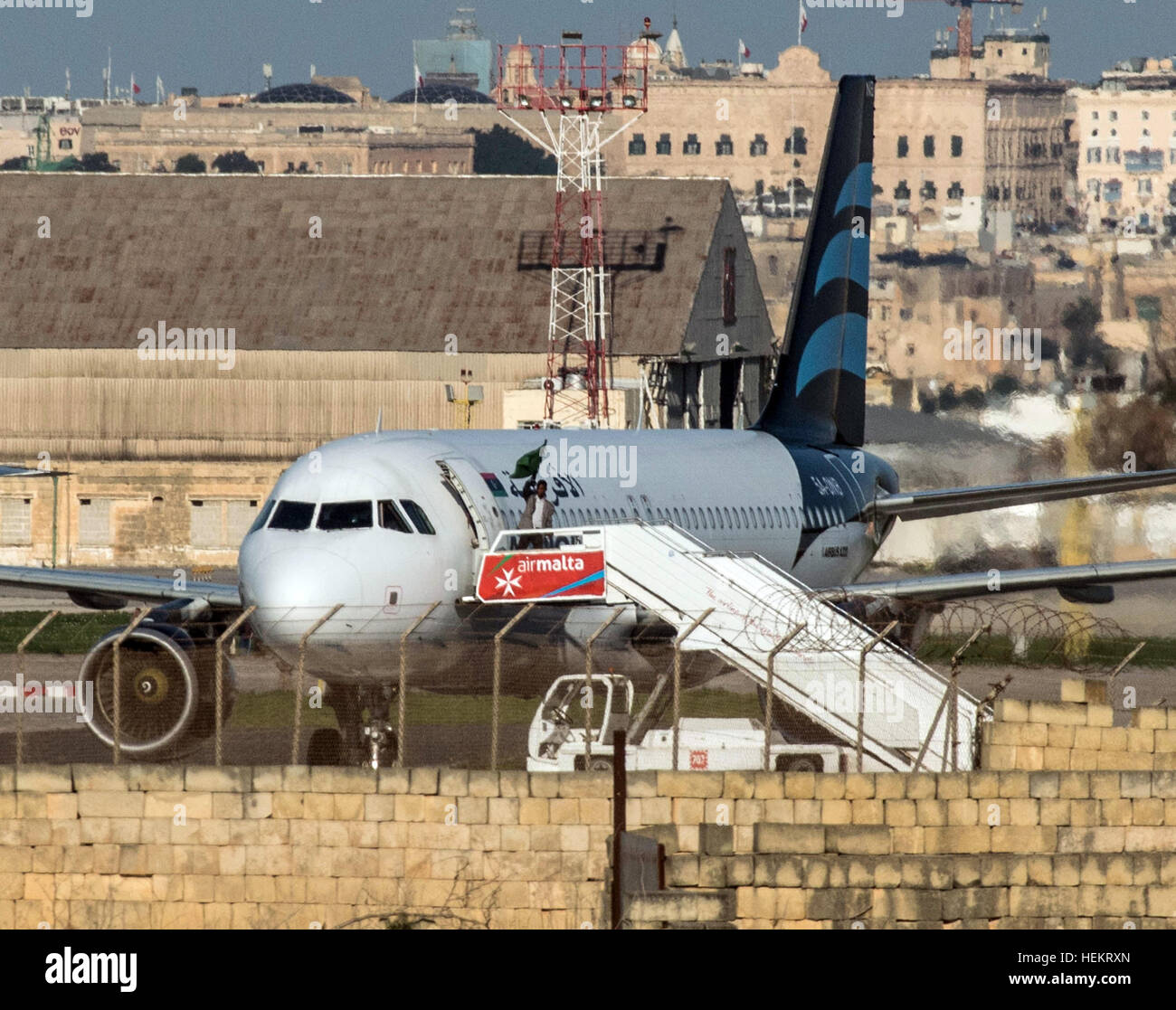 One of the kidnappers turning a green, old Libyan state flag which was abolished in 2011 after the fall and death of Gaddafi while leaving the plane at the airport of Valletta, Malta, 23 December 2016 The hijacking of the Afriqiyah-Airways flight 8U209 with more than 100 people on board has come to an end without violence. The two hijackers surrendered to Maltese security forces. Photo: Stephen Busuttil/dpa Stock Photo