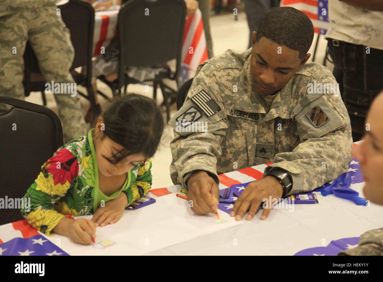 A U.S. Army soldier sits and colors a picture with a young Iraqi girl during Iraqi Kids' Day at Joint Base Balad in Salah Aldin province, Iraq, Oct. 1, 2011. The purpose of Iraqi Kids' Day is to build positive relations with Iraqi children, let them know that the U.S. forces in Iraq are friendly and are here to help the well-being of Iraq's citizens. All these soldiers and airmen are in Iraq in support of Operation New Dawn. (Photo by Pfc. Nikko-Angelo Matos) Iraqi Kids' Day 111001-A-YV529-014 Stock Photo