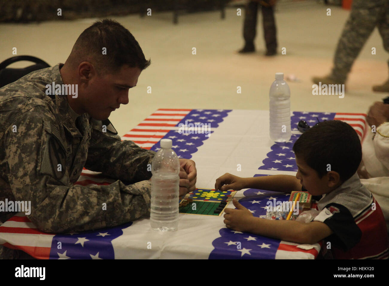 A U.S. Army soldier of 2nd Advise and Assist Brigade, 1st Cavalry Division, plays a board game with an Iraqi boy during Iraqi Kids' Day at Joint Base Balad in Salah Aldin province, Iraq, Oct. 1, 2011. The purpose of Iraqi Kids' Day is to build positive relations with Iraqi children, let them know that the U.S. forces in Iraq are friendly and are here to help the well-being of Iraq's citizens. All these soldiers and airmen are in Iraq in support of Operation New Dawn. (Photo by Pfc. Nikko-Angelo Matos) Iraqi Kids' Day 111001-A-YV529-030 Stock Photo