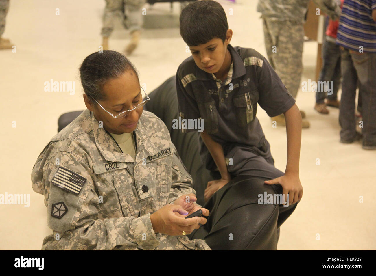 A U.S. Army soldier shows the capabilities of her smart phone to an Iraqi boy at Joint Base Balad in Salah Aldin province, Iraq, Oct. 1, 2011. The purpose of Iraqi Kids' Day is to build positive relations with Iraqi children, let them know that the U.S. forces in Iraq are friendly and are here to help the well-being of Iraq's citizens. All these soldiers and airmen are in Iraq in support of Operation New Dawn. (Photo by Pfc. Nikko-Angelo Matos) Iraqi Kids' Day 111001-A-YV529-055 Stock Photo