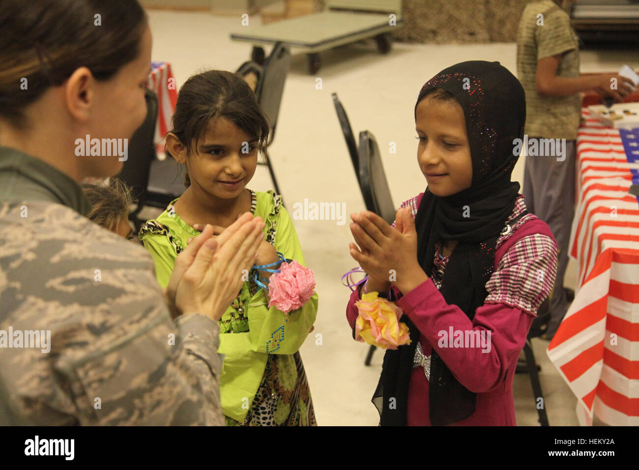 A U.S. Air Force airman teaches a young Iraqi girl how to play 'patty cake' during Iraqi Kids' Day at Joint Base Balad in Salah Aldin province, Iraq, Oct. 1, 2011. The purpose of Iraqi Kids' Day is to build positive relations with Iraqi children, let them know that the U.S. forces in Iraq are friendly and are here to help the well-being of Iraq's citizens. All these soldiers and airmen are in Iraq in support of Operation New Dawn. (Photo by Pfc. Nikko-Angelo Matos) Iraqi Kids' Day 111001-A-YV529-060 Stock Photo
