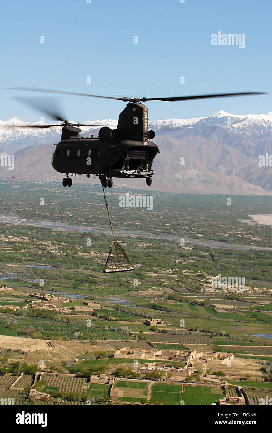 BAGRAM AIRFIELD, Afghanistan —A CH-47 Chinook helicopter flown by aviators from Task Force Falcon carry a sling-loaded I-beam from the World Trade Center and display an American flag above Parwan province, Afghanistan, March 31. The beam, which is nine feet long and two feet wide and weighs more than 950 pounds, was donated to the U.S. military by the residents of Breezy Point, New York through an organization called Sons and Daughters of America, Breezy Point. (Photo by U.S. Army Sgt. Spencer Case, 304th Public Affiars Detachment) A Fitting Tribute, Word Trade Center I-Beam Finds Home in Afgh Stock Photo