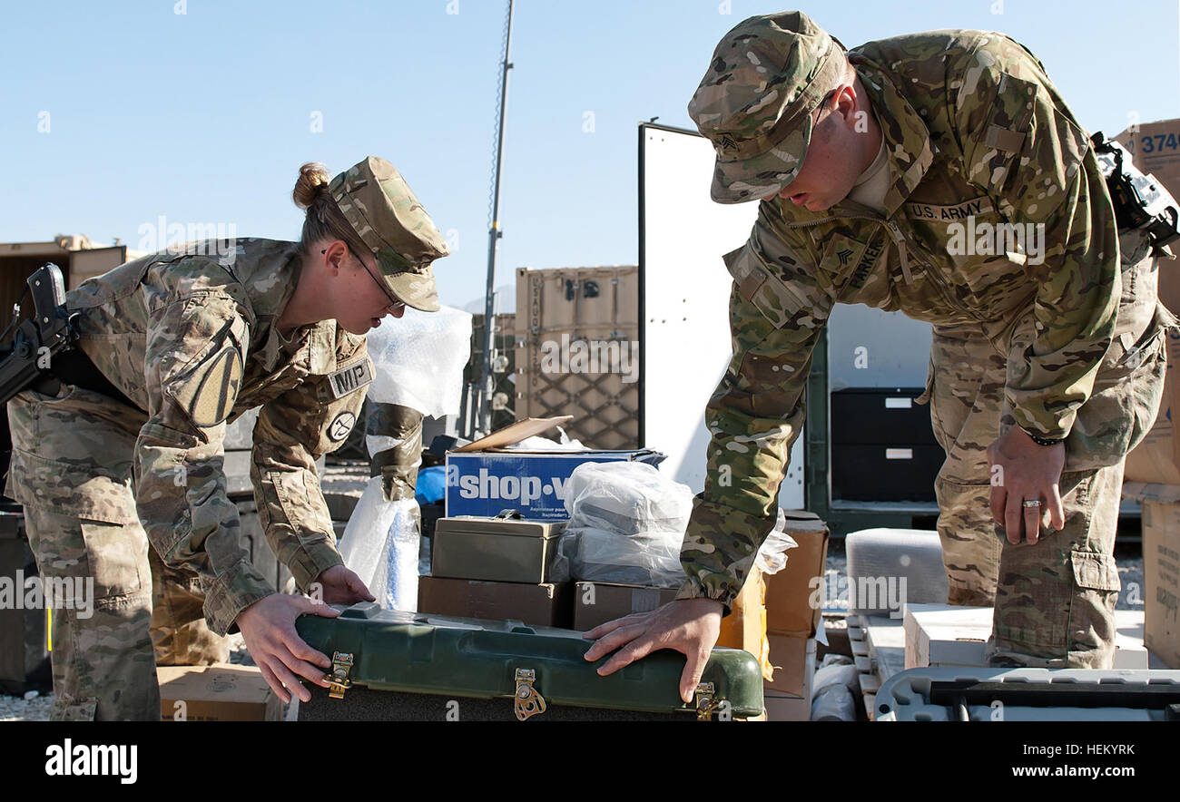 Sgt. Christopher C. Parker (right), a native of Oak Hill, W.Va., a military police patrol supervisor, and Spc. Stephanie Brown, a native of Lost Creek, W.Va., a traffic accident investigator, both in the 156th Military Police Detachment, attached to the 1st Air Cavalry Brigade, 1st Cavalry Division, inspect supplies that are being shipped back to the U.S. as soldiers of the 155th Inland Cargo Transfer Company, 10th Transportation Battalion, 7th Sustainment Brigade prepare to redeploy back to Fort Eustis Oct. 24. Customs checks all equipment and supplies that are to be shipped back to the U.S.  Stock Photo