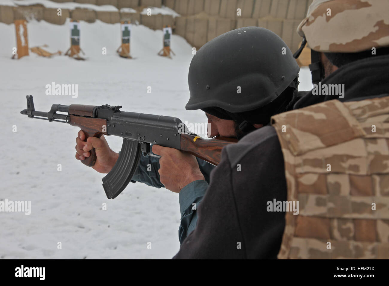An Afghan Uniformed Police officer fires his AK47 rifle under the