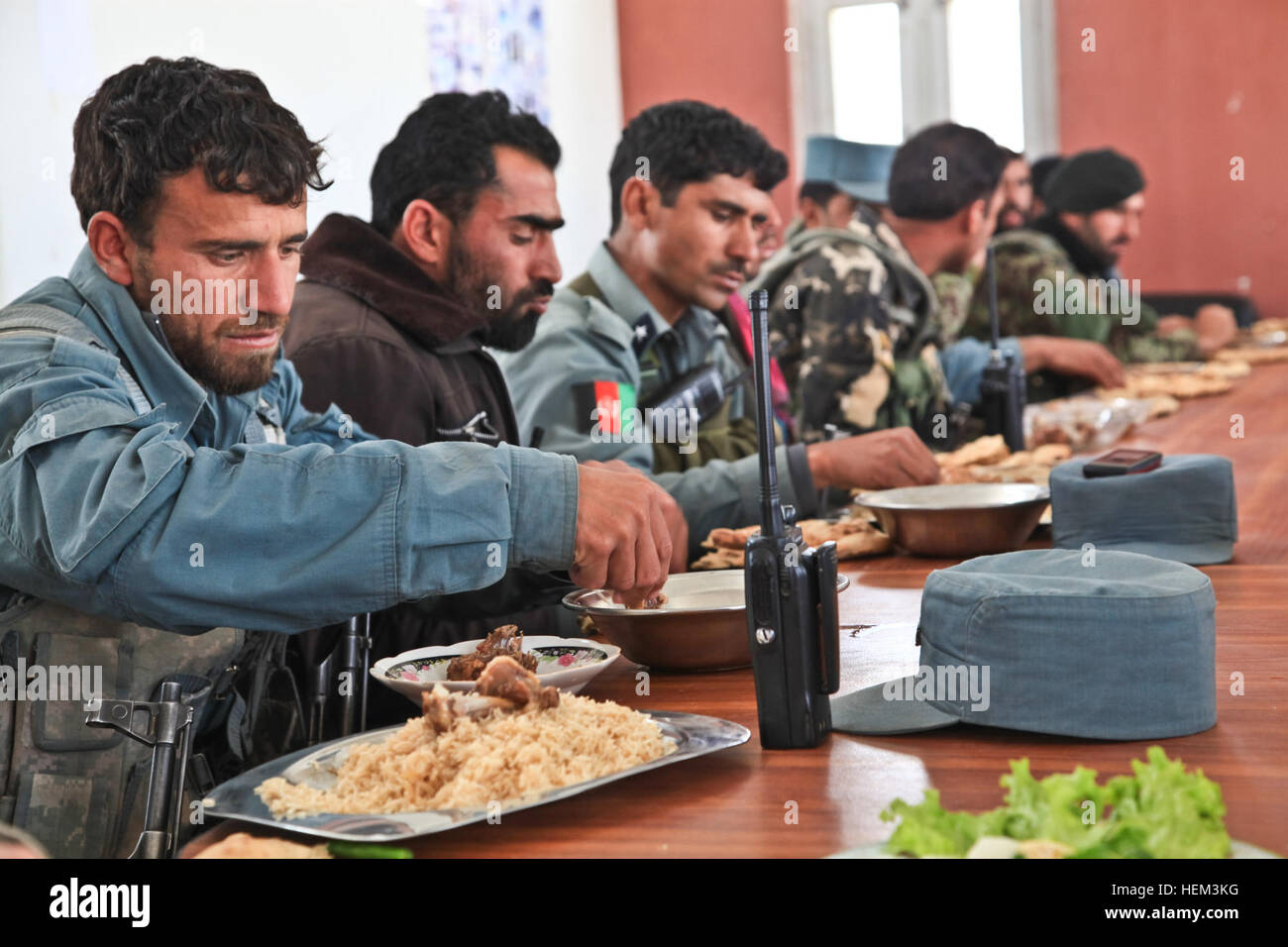 Members of the Afghan Uniformed Police eat lunch with soldiers of the Afghan National Army, Nazyan district, Nangarhar province, Afghanistan, March 15, 2012. The purpose of the mission was to gain familiarization of the district and key leadership. Key leader engagement 120315-A-LP603-120 Stock Photo