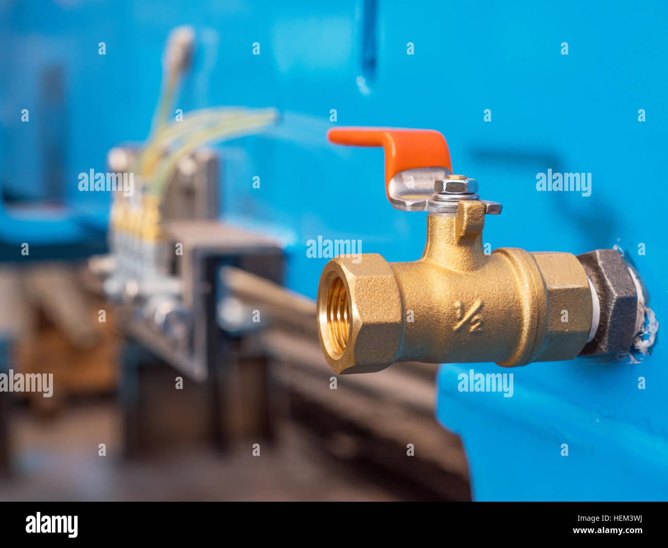 Half inch brass ball valve in industrial setting. Shallow depth of field with the valve in focus. Stock Photo