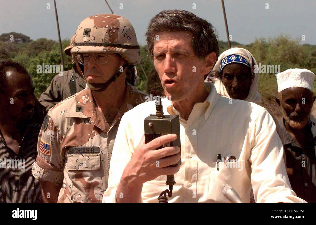 Special Envoy to Somalia, Ambassador Robert Oakley, is seen from the chest up, facing the camera and speaking to a group of Somalis over a public address system.  Behind him and to the left is US Army BGEN Lawson W. Magruder III, Vice Commander, 10th Mountain Division (Light), in Somalia as the Commander of Combined Task Force Kismayo.  Somali civilians stand in the background.  This mission is in direct support of Operation Restore Hope. Robert Oakley in Somalia Stock Photo