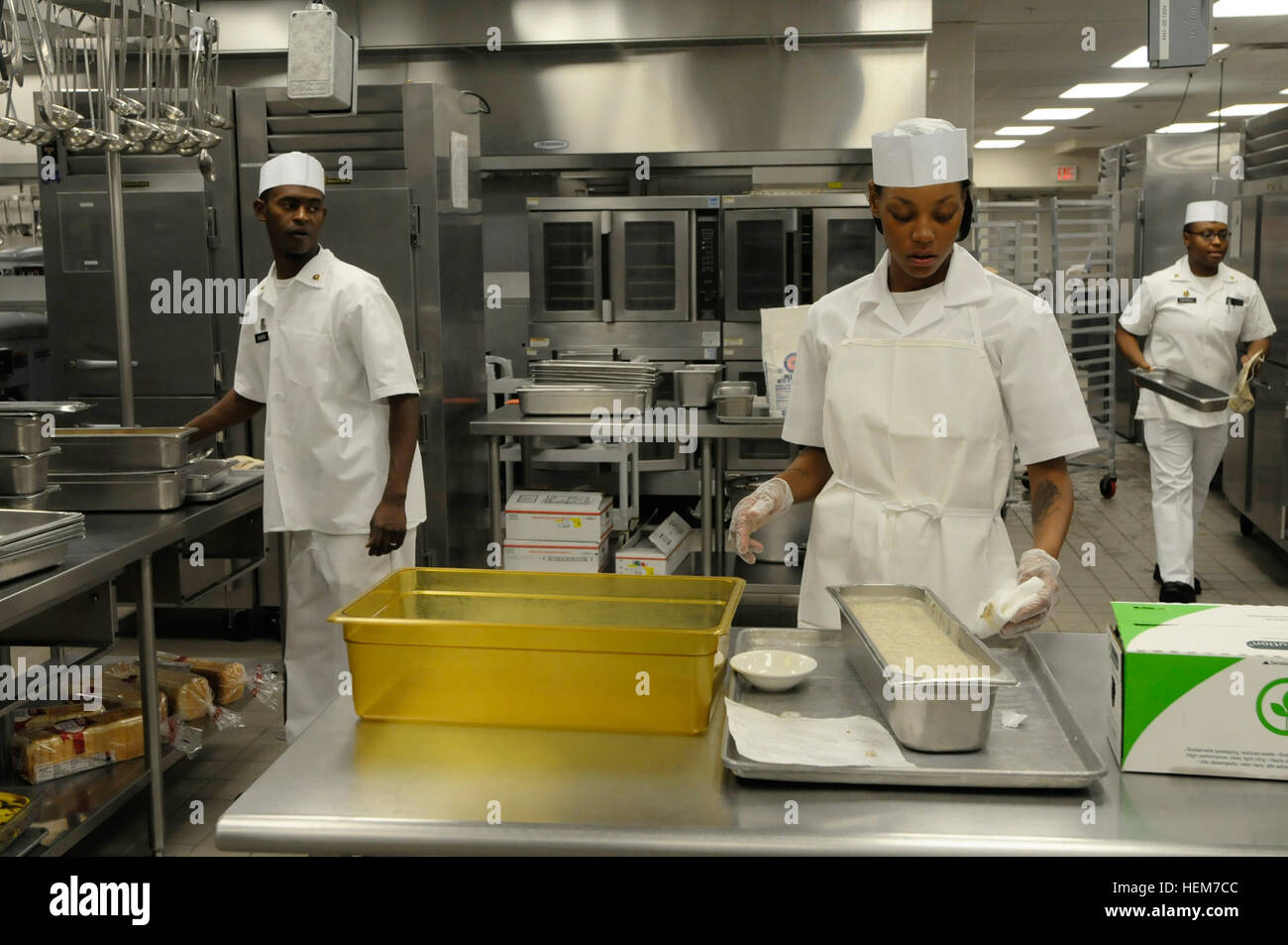 U.S. Army Pvt. Brinette Gibbs, (center), a native of Washington D.C., a food service specialist assigned to 377th Transportation Company, 15th Sustainment Brigade, prepares wipes the edge of a gravy tray prior to morning food service operations at Area 1 dining facility, June 20, 2012. She and other food service specialists prepare breakfast and lunch ahead of the second shift, which focuses on preparing dinner for soldiers on Biggs Army Airfield. Food service specialists provide quality meals for Fort Bliss personnel 626104 Stock Photo