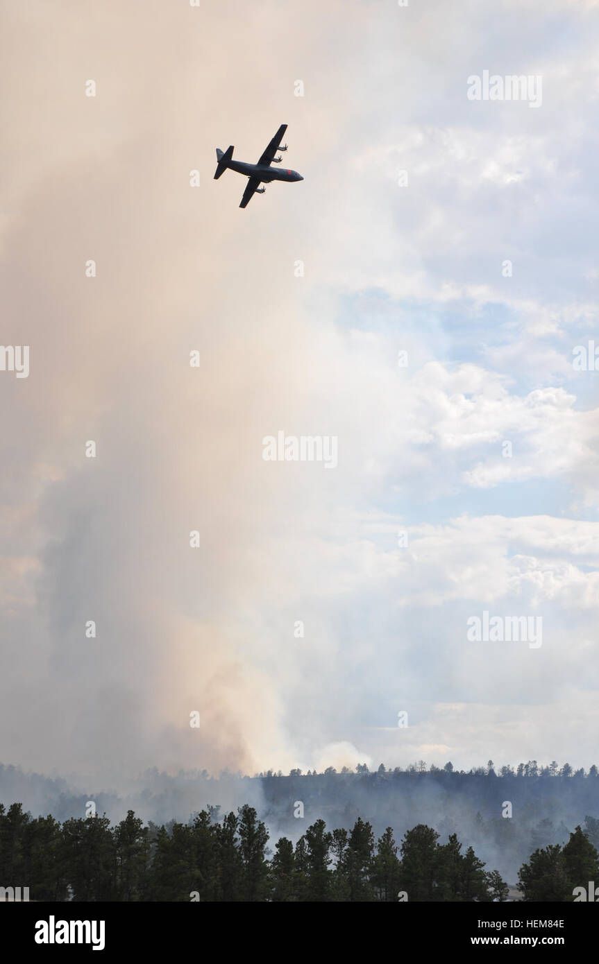 A California Air National Guard C-130, carrying the Modular Airborne Fire Fighting System, flies over smoke and fire from the Sawmill Canyon Fire on the Camp Guernsey Joint Training Center's North Training Area, July 16, 2012. The fire began July 14 and consumed 9.600 acres of timber and grass by July 17. MAFFS is a self-contained aerial firefighting system owned by the U.S. Forest Service that can discharge 3,000 gallons of water or fire retardant in less than five seconds, covering an area one-quarter of a mile long by 100 feet wide. Sawmill Canyon fire 120716-A-VN194-843 Stock Photo