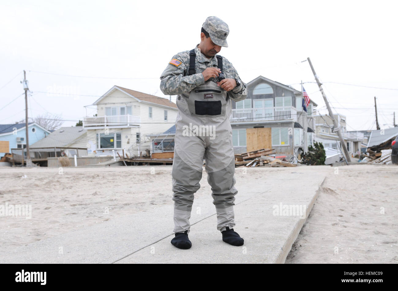 Spc. Faisal Baz from the 227th Preventive Medicine Detachment, 56th Multifunctional Medical Battalion, 62nd Medical Brigade, out of Joint Base Lewis-McChord, Wash., dons personal protective equipment before collecting water samples in Breezy Point, N.Y., Nov. 10. He collected samples of water being pumped from flooded houses to send off to be tested at the Public Health Compound at Aberdeen Proving Grounds, Md. Breaking barriers in service of country 781040 Stock Photo