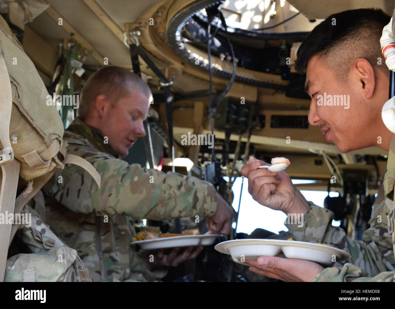 Army Spc. Peter Chang (right), and U.S. Army Spc. Zach Whiteman (left), members of the personal security detail from Headquarters and Headquarters Battery, 3rd Battalion, 320th Field Artillery Regiment, 101st Airborne Division (Air Assault), eat Christmas lunch inside a MaxxPro Mine Resistant Ambush Protected vehicle at Combat Outpost Justice, Afghanistan, Dec. 25, 2012. The detail was posted outside the dining facility while U.S. Army Brig. Gen. Clarence Chinn, Deputy Commander, Regional Command East, visited with U.S. Army Soldiers and Afghan Uniformed Police during the holiday meal. (U.S. A Stock Photo