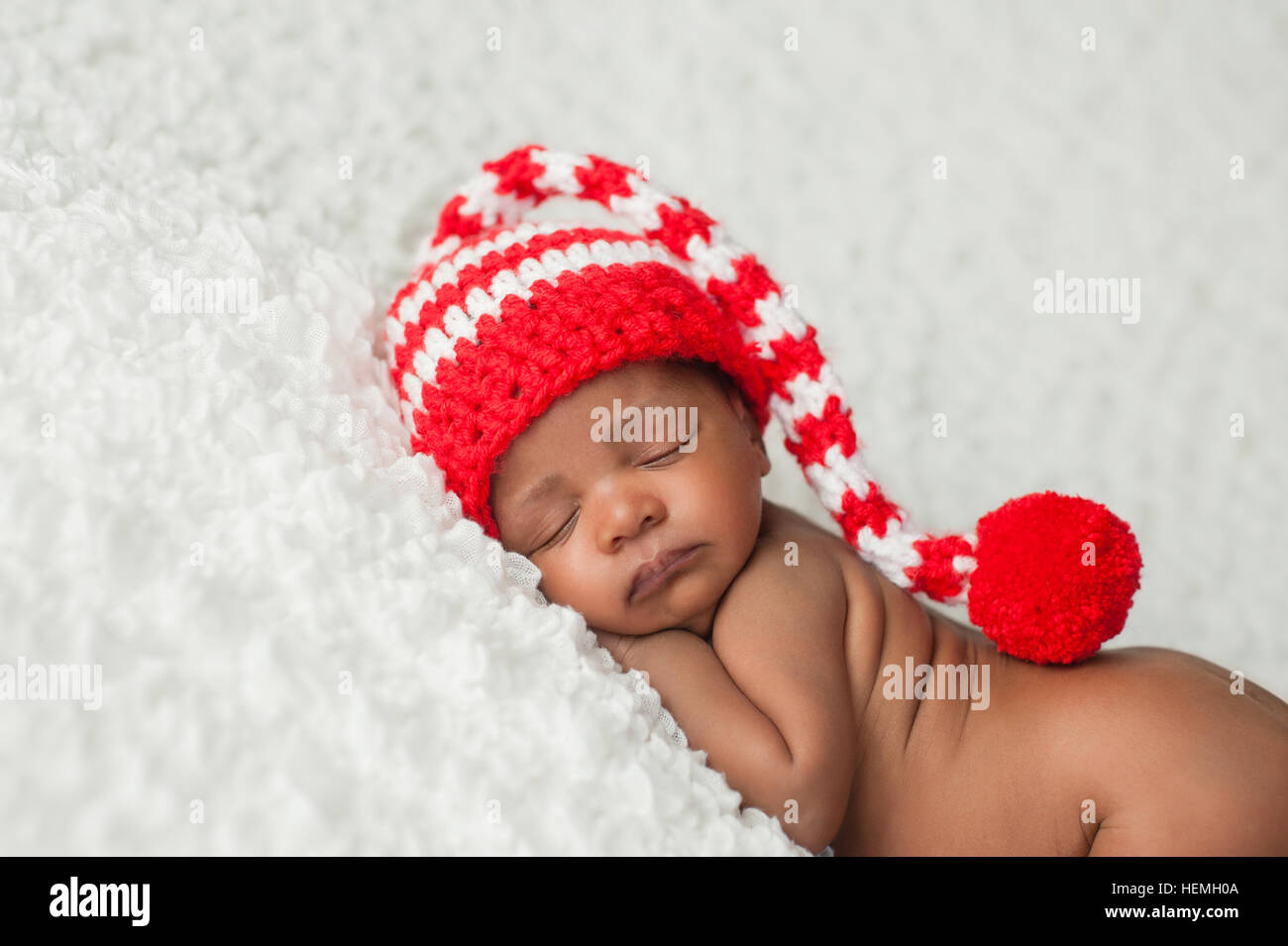 A one month old baby wearing a white and red, crocheted stocking cap