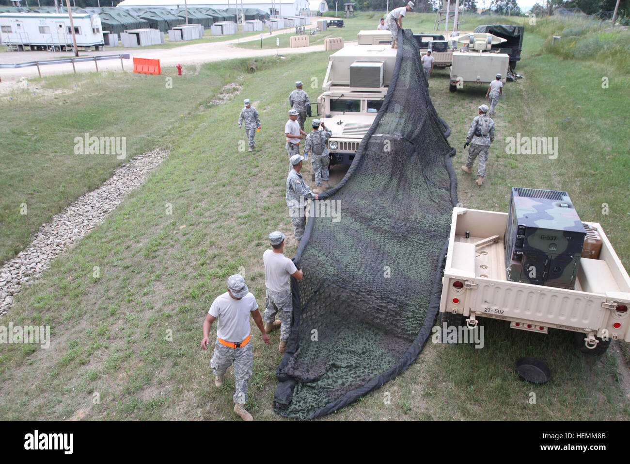 Soldiers from the 829th Signal Company, 303rd Maneuver Enhancement Brigade assemble tactical camouflage netting to their work area July 14 at Fort McCoy, WI. The soldiers are preparing for start of the brigade's war exercise, Operation Compass Shield, scheduled to take place there July 23-30. (Photo by Spc. David Harthcock) Soldiers of the 829th Signal Company set up their area of operation at 2013 WAREX 130714-A-VH612-134 Stock Photo