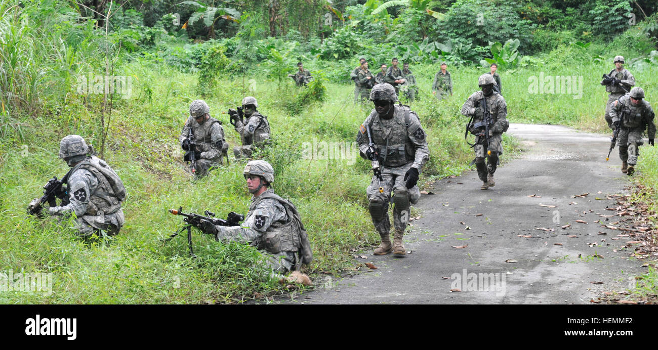 Soldiers from 4th Battalion, 23rd Infantry Regiment, 2nd Brigade, 2nd Infantry Division react to direct contact while their counterparts from Charlie Company, 2nd Battalion, Singapore Infantry Regiment look on during a jungle familiarization squad battle course near Amoy Quee Camp, Singapore, July 18. This is the first time these soldiers were introduced to the Singapore jungle environment during a simulated battlefield. (U.S. Army photo by Spc. Tyler Meister) US Army expands knowledge of jungle tactics 130718-A-NO327-103 Stock Photo