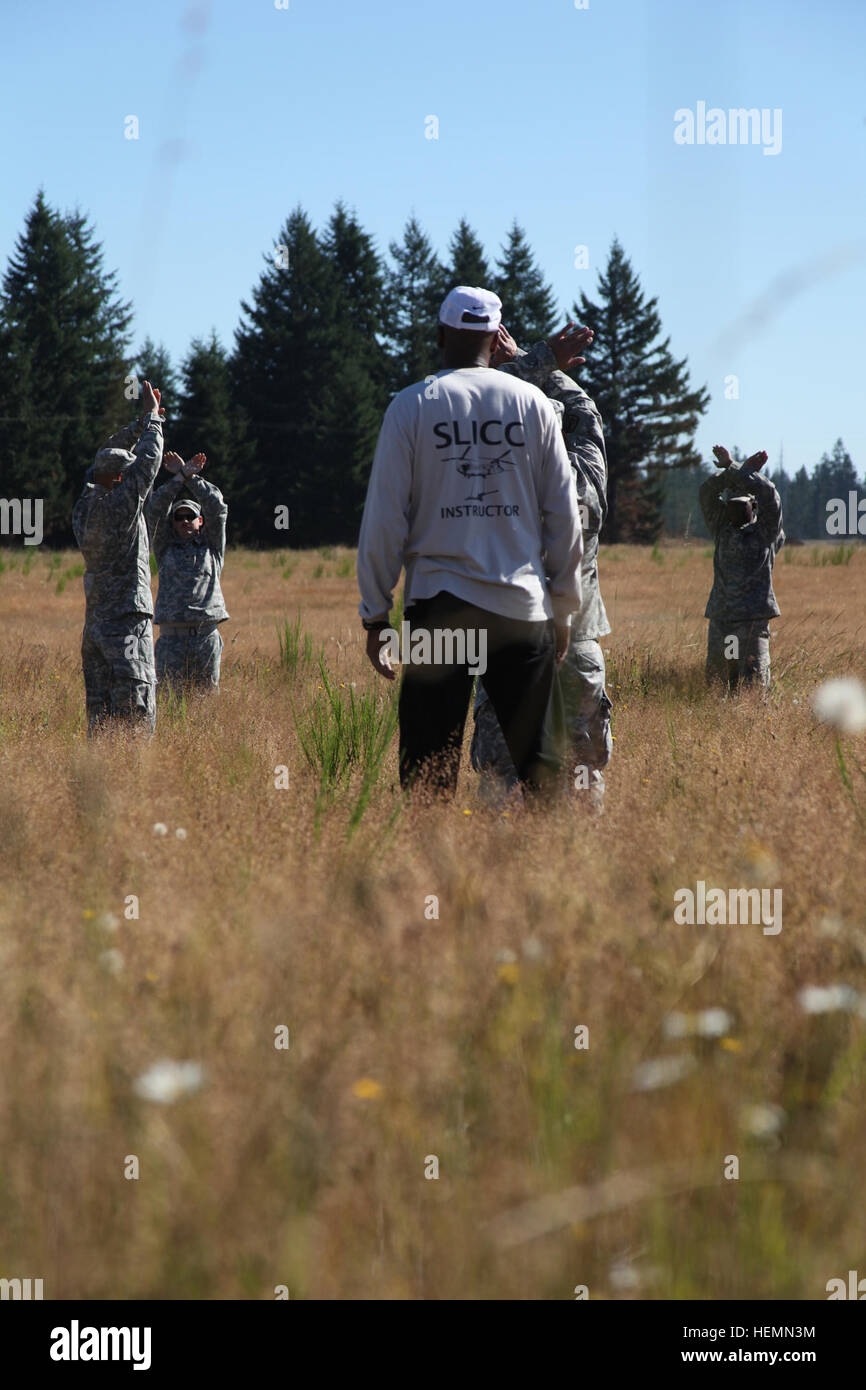 Instructors from the U.S. Army Quartermaster School in Fort Lee, Va., assist soldiers as they practice hand-and-arm singles for aircraft July 26 at a range on Joint Base Lewis-McChord as part of the practical exercise portion of the Sling Load Inspector Certification Course. JBLM soldiers qualify to load up, lift off 130736-A-XP915-020 Stock Photo