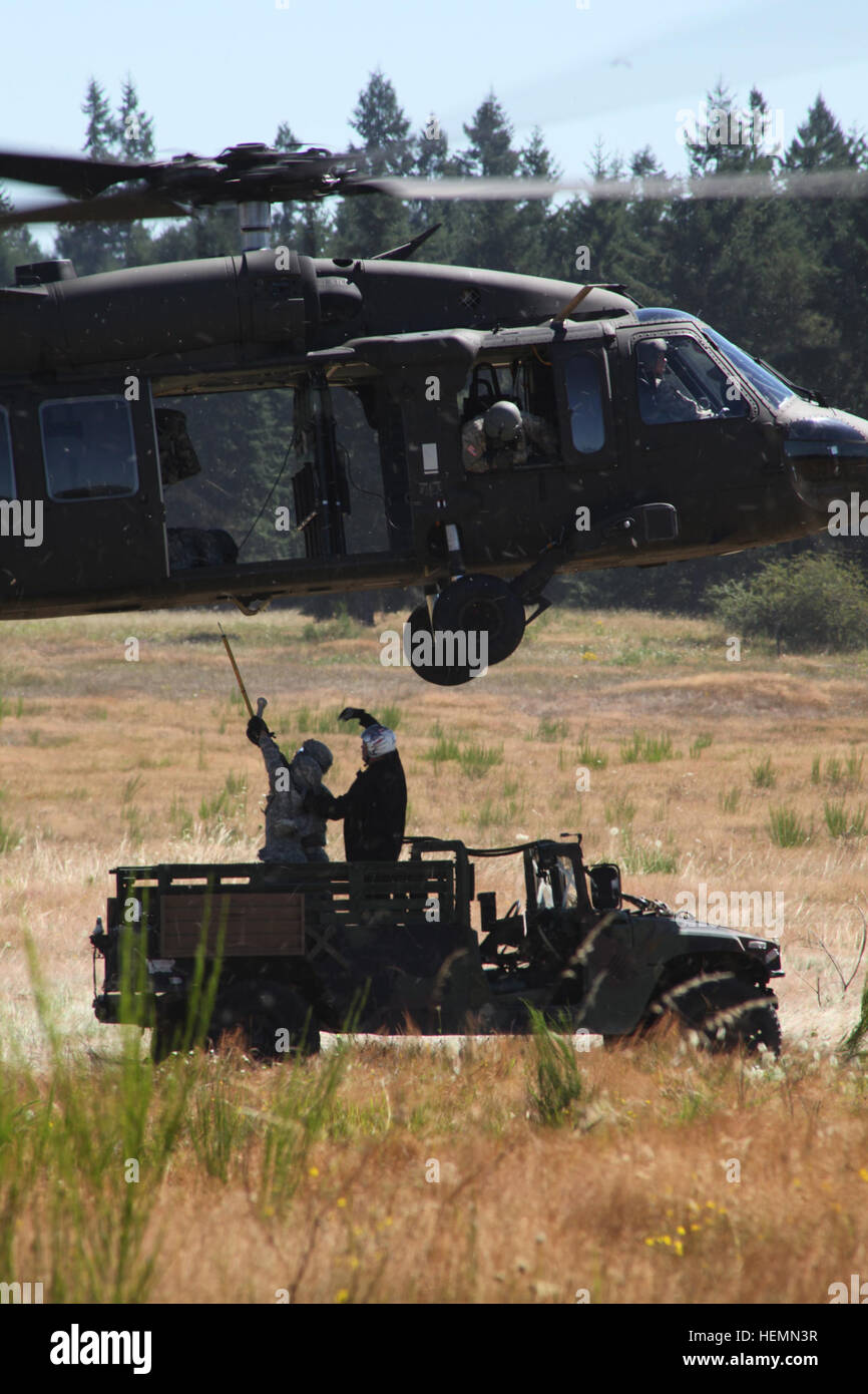Instructors of the U.S. Army Quartermaster School at Fort Lee, Va., assist Soldiers as they attempt to attach a Humvee to a UH-60M Black Hawk helicopter at a range as part of the practical exercise portion of the Sling Load Inspector Certification Course at Joint Base Lewis-McChord, Wash., July 27, 2013. (U.S. Army photo by Staff Sgt. Bryan Lewis/Released) JBLM soldiers qualify to load up, lift off 130726-A-XP915-045 Stock Photo