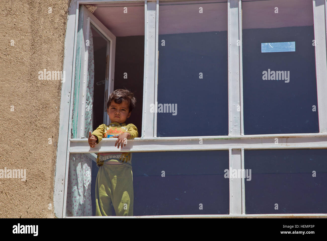 An Afghan boy stands in the window during a medical seminar in Deh Yak district, Ghazni province, Afghanistan, August 19, 2013. Fifty men, women, and children from Pajak village and surrounding areas attended the medical seminar, which covered topics such as first aid, sanitation, emergency birthing techniques, and nutrition.  (U.S. Army photo by Spc. Jessica Reyna DeBooy/Released) Enduring Freedom 130820-A-SL739-041 Stock Photo